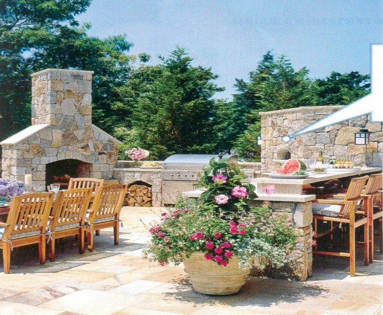 Outdoor stone kicthen area with seating area, stone fireplace, grill, and tables