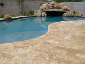 Travertine pool patio in front of pool and stone water feature