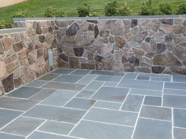 Blue flagstone patio in front of decorative stone wall