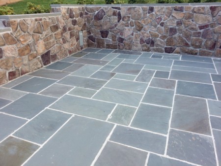 Blue stone pavers in front of a decorative stone wall