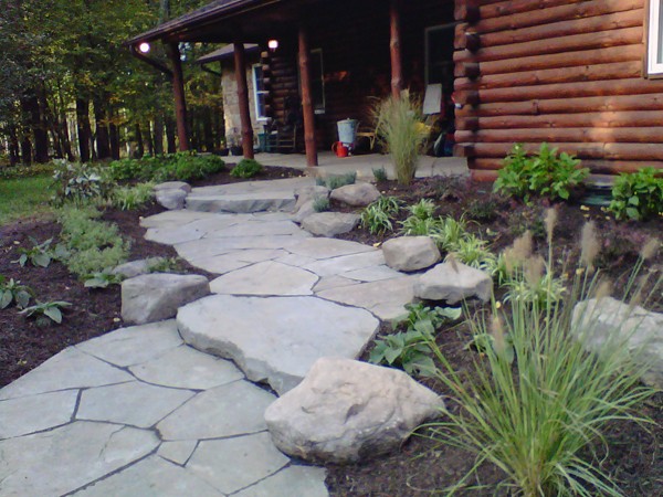 Landscape boulders in outdoor garden leading up to a house