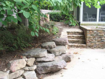 Landscape boulders in a backyard leading up to stone steps